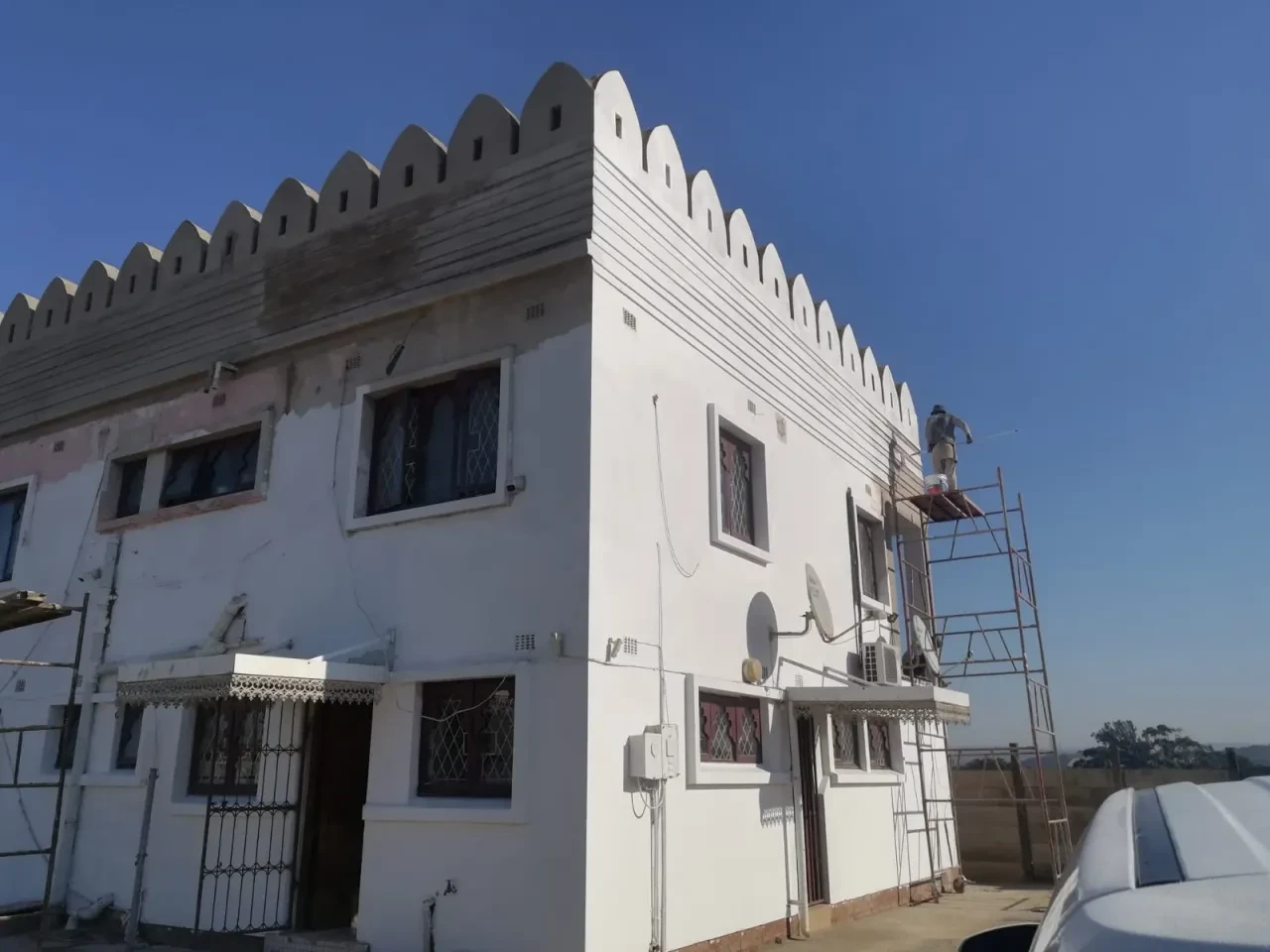 Project site — white building with crenellated parapet under finishing works