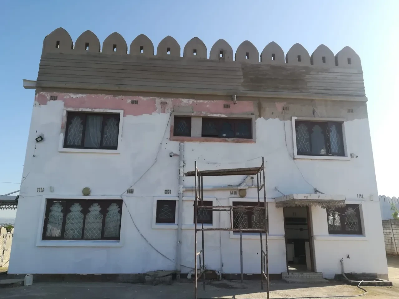Project site — white building with scaffolding under renovation crenellated parapet