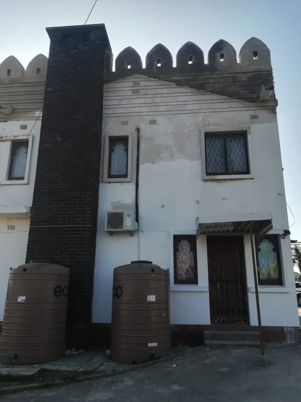 Project site — white and black crenellated building facade with arched windows