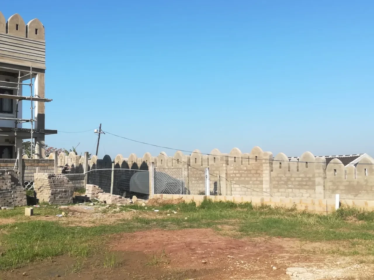 Project site — stone buildings under development with crenellated walls