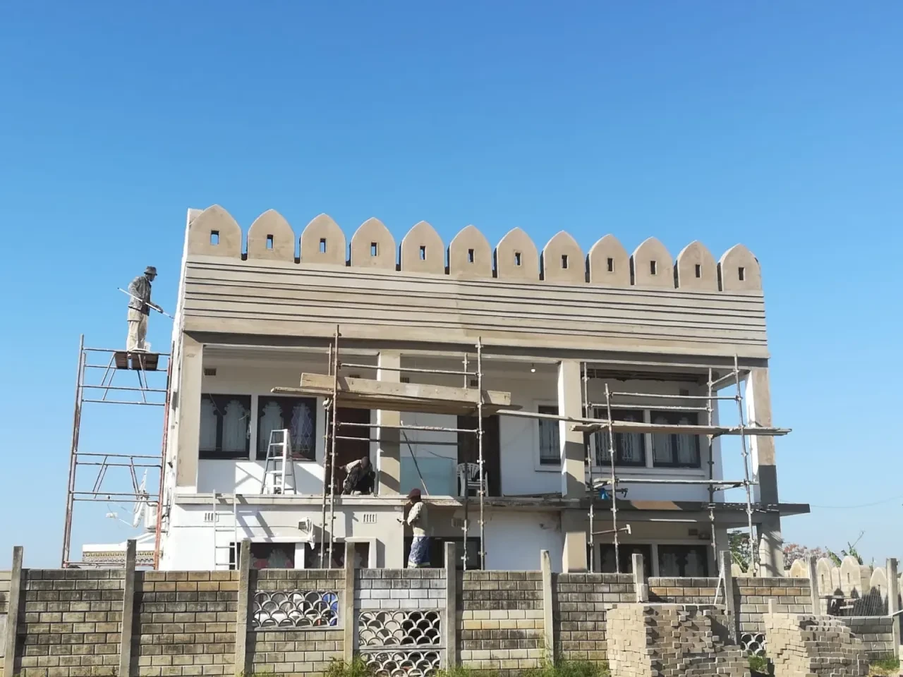 Project site — residential building under construction with crenellated roofline and arched windows