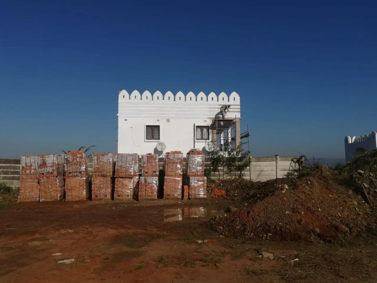 Project site — fortified white structure with crenellations and brick on arid site