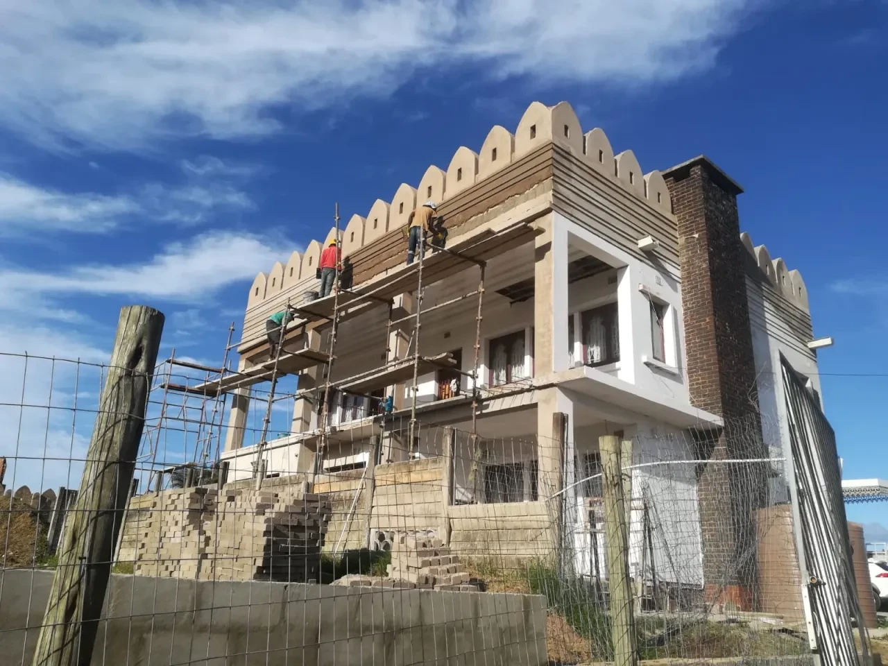 Project site — multi-storey building under construction with crenellated parapet and scaffolding