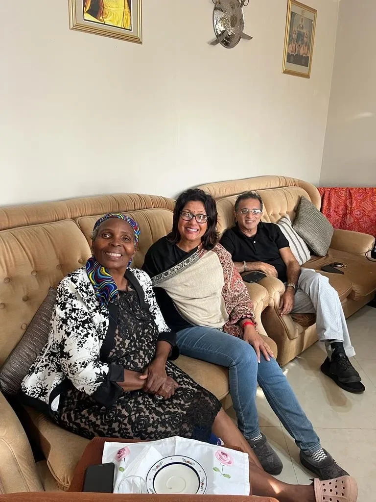 Project site — three people seated on sofa in home interior, community meeting