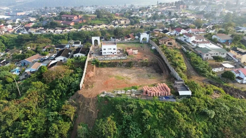 Project site — aerial view of large cleared site with crenellated perimeter wall and Durban hillside