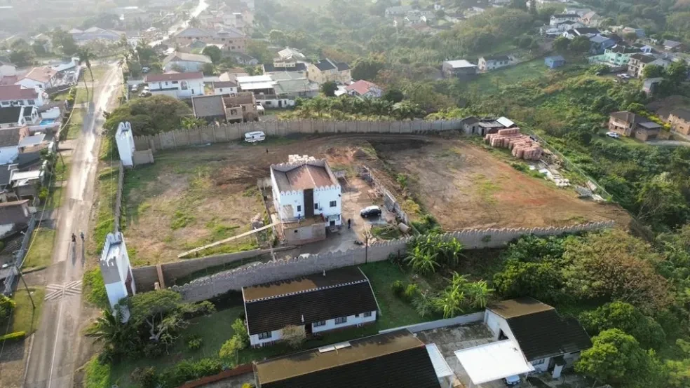 Project site — aerial view of crenellated compound with white building and cleared grounds