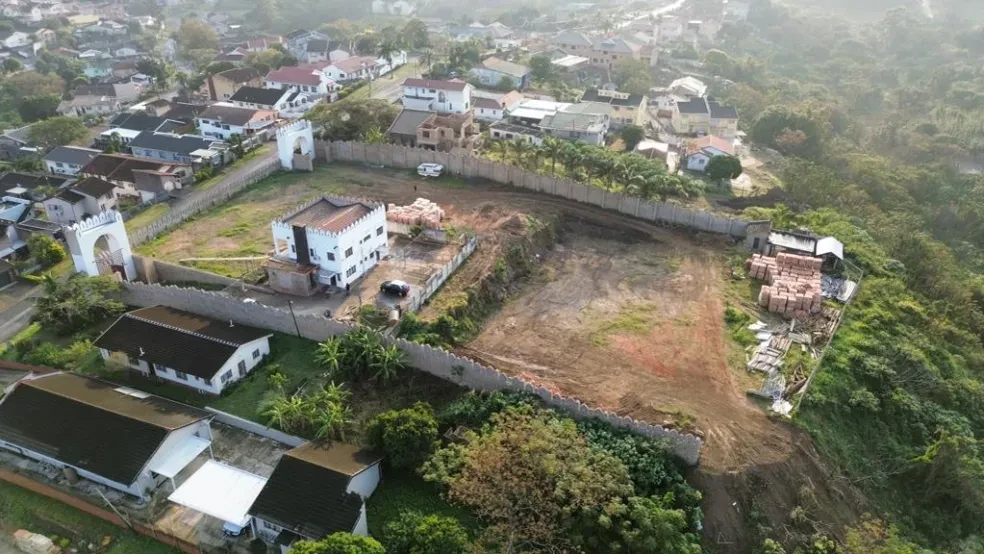 Project site — aerial view of crenellated compound with cleared site and Durban suburb