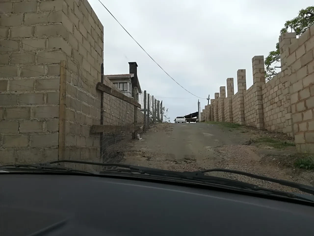 Project site — concrete block boundary walls lining dirt road