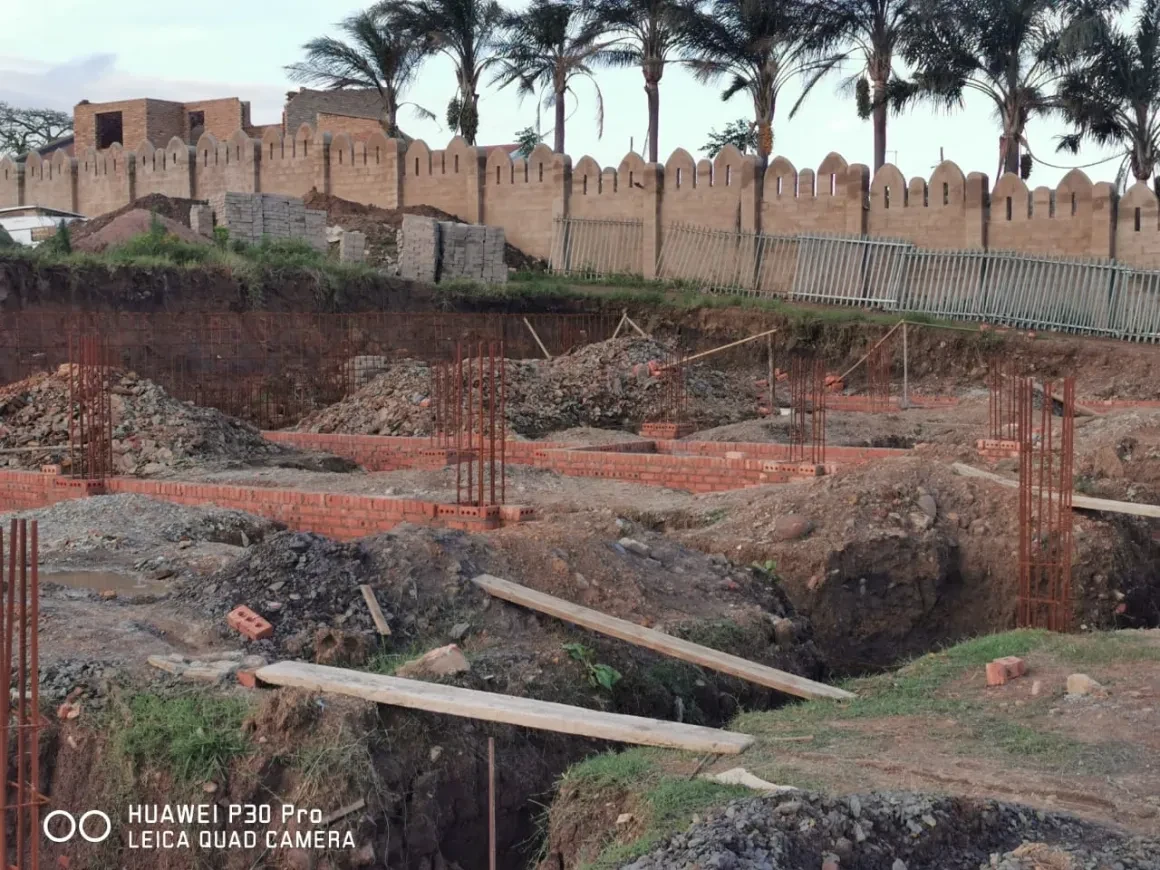 Project site — aerial overhead view of tiled roof with workers and crenellated parapet