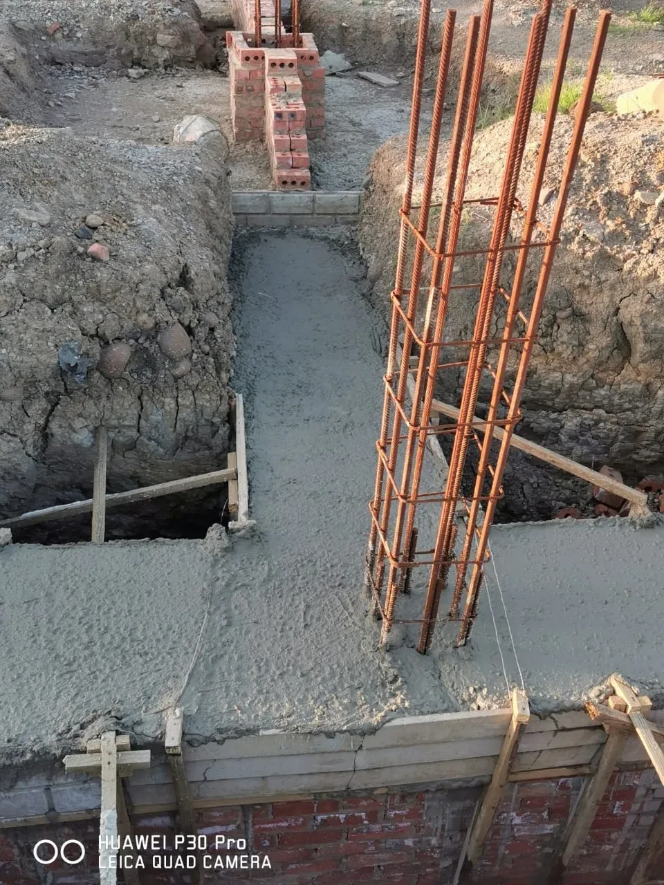 Project site — concrete foundation with rebar cage and brick column footings in excavation