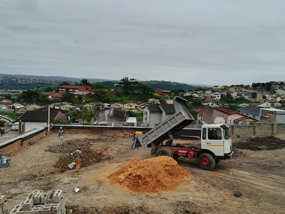Project site — dump truck delivering sand to construction site
