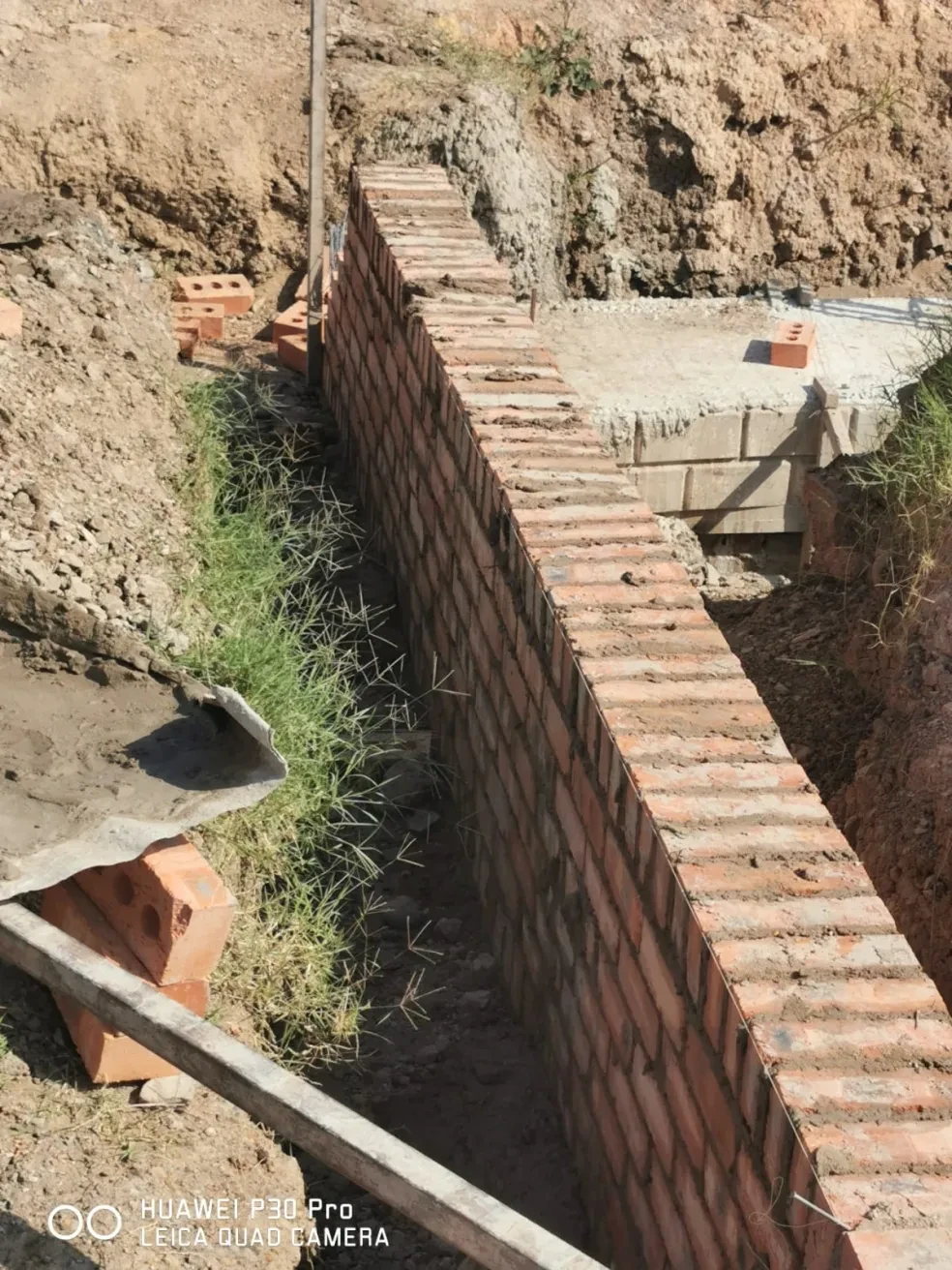 Project site — brick retaining wall in excavation trench with concrete strip footing and earthwork