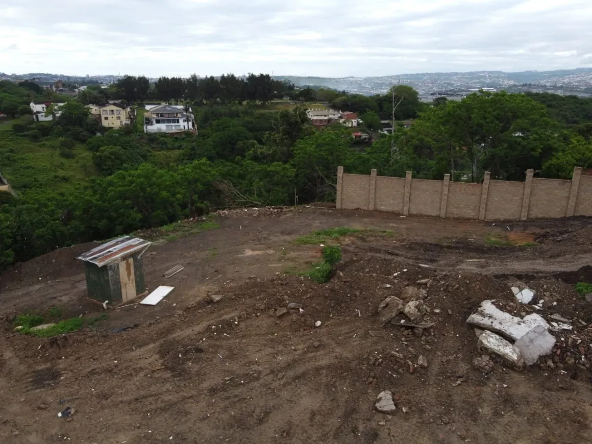 Project site — cleared land with perimeter wall and city view
