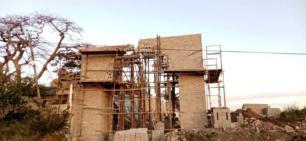 Project site — brick arch gateway with scaffolding, arch partially formed with timber centering