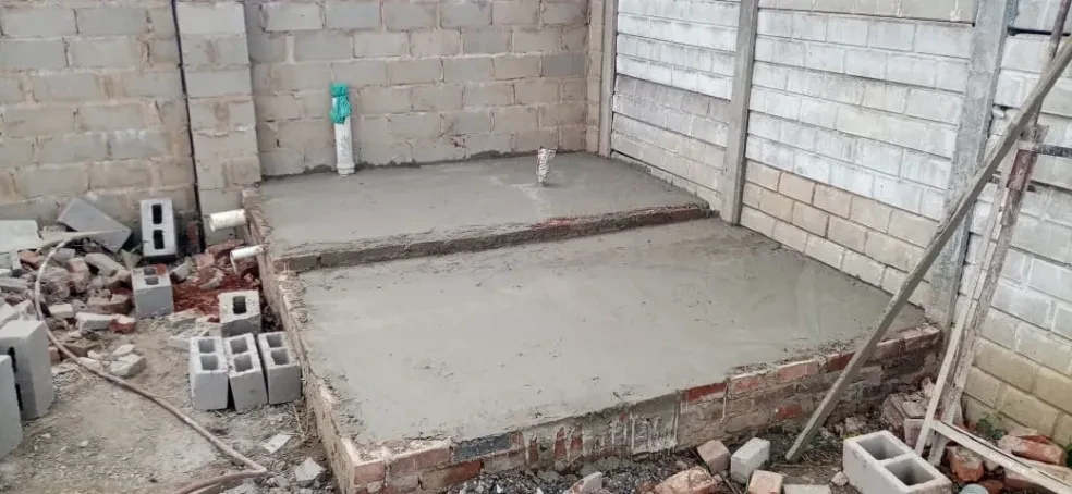 Project site — concrete foundation slab with plumbing stubs inside concrete block walls