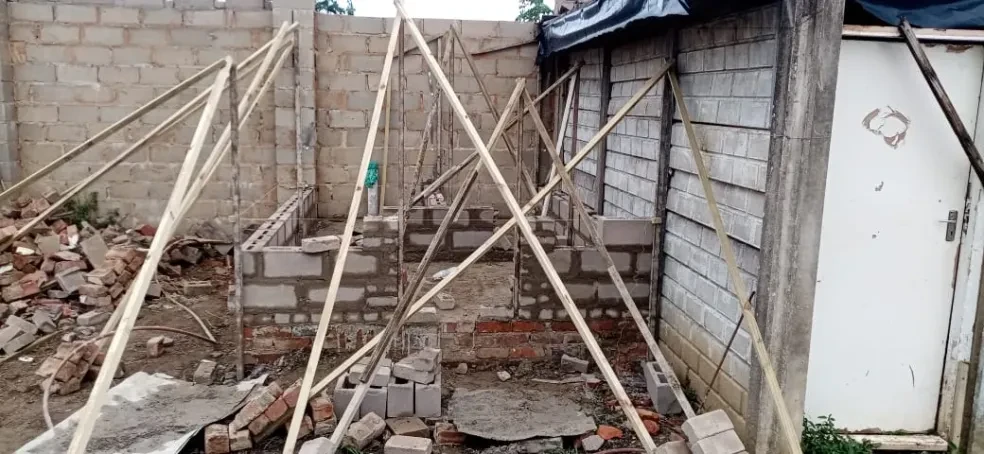 Project site — interior concrete block walls with wooden bracing poles and brick debris