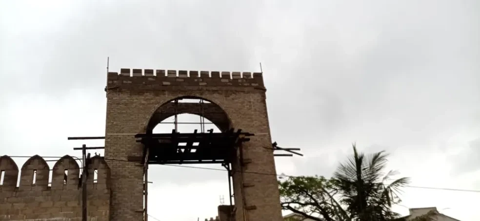 Project site — large brick arch gateway with crenellated parapet and wooden scaffolding inside arch