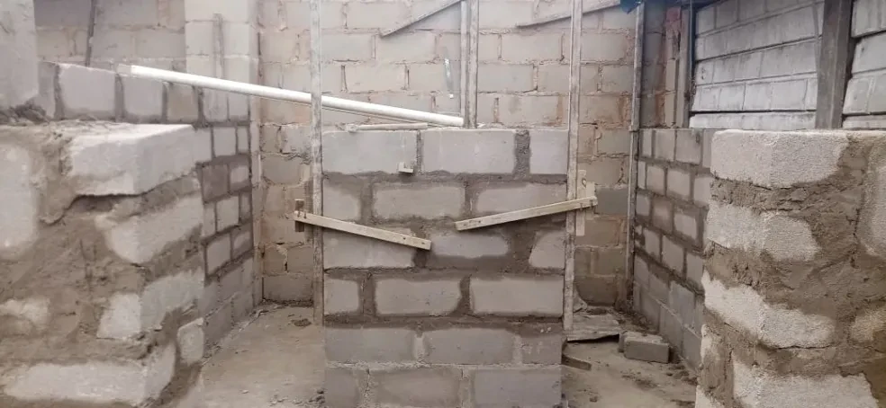 Project site — interior concrete block room with PVC pipe and wooden bracing