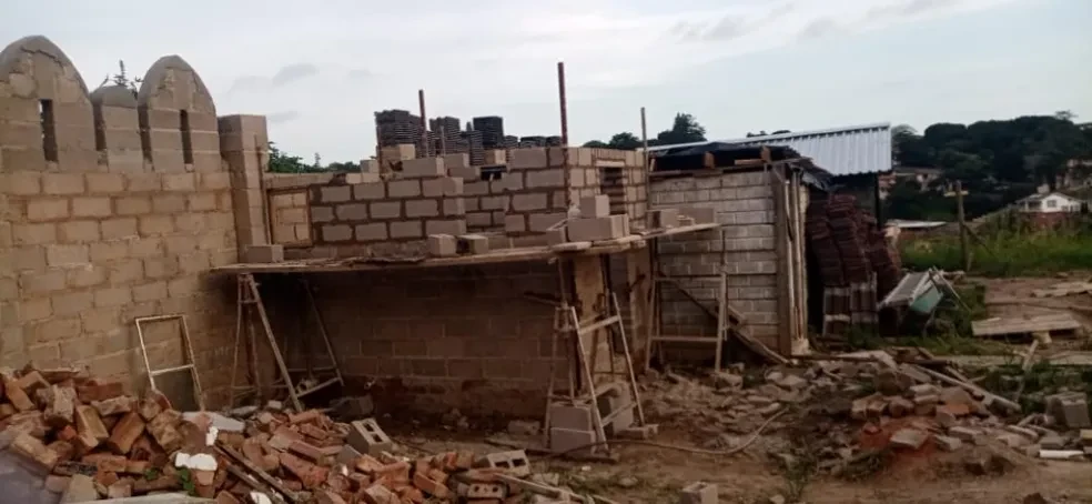 Project site — concrete block building under construction with wooden scaffolding and brick rubble