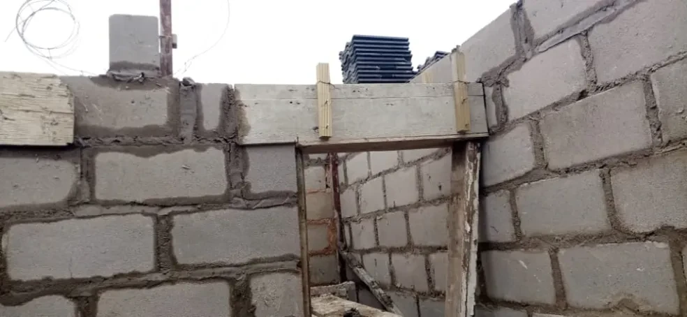 Project site — concrete block walls with wooden door frame and stacked roof tiles visible above