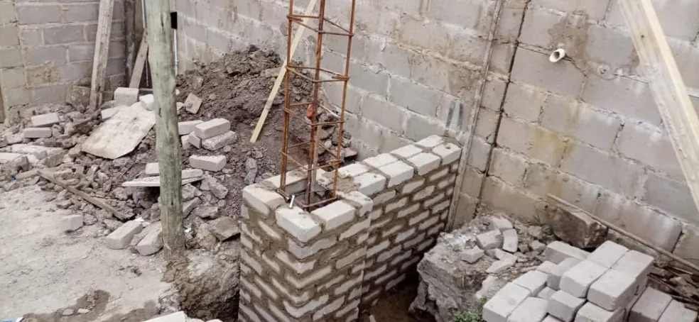 Project site — interior concrete block walls with rebar column and brick rubble on floor