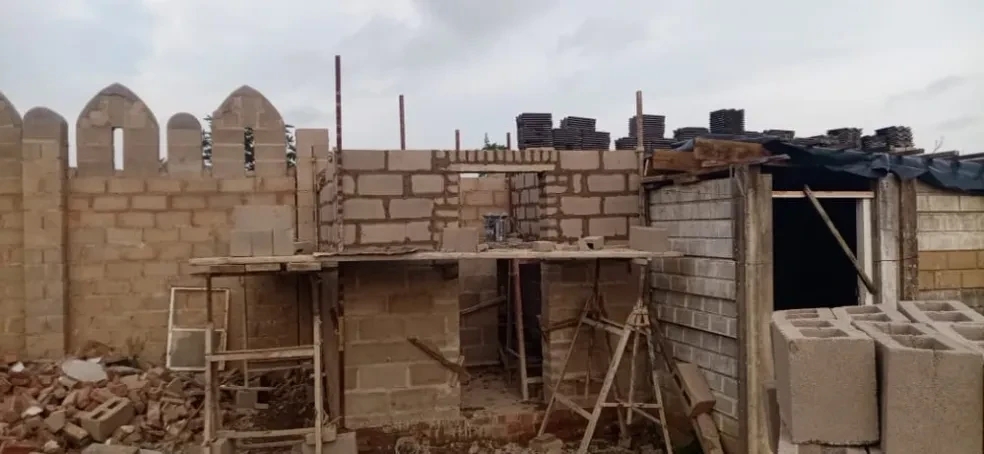 Project site — brick building under construction with scaffolding and crenellated perimeter wall
