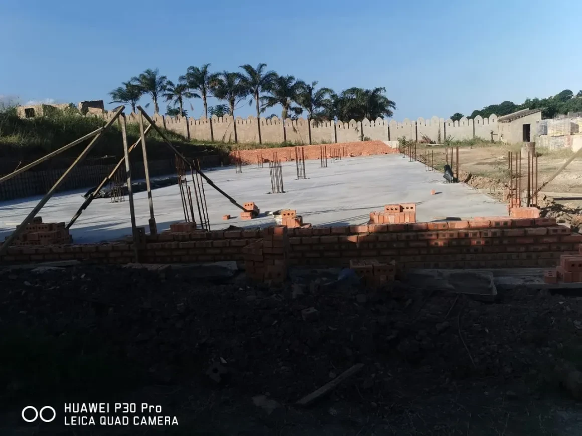 Project site — concrete slab with rebar columns and crenellated perimeter wall, overcast sky