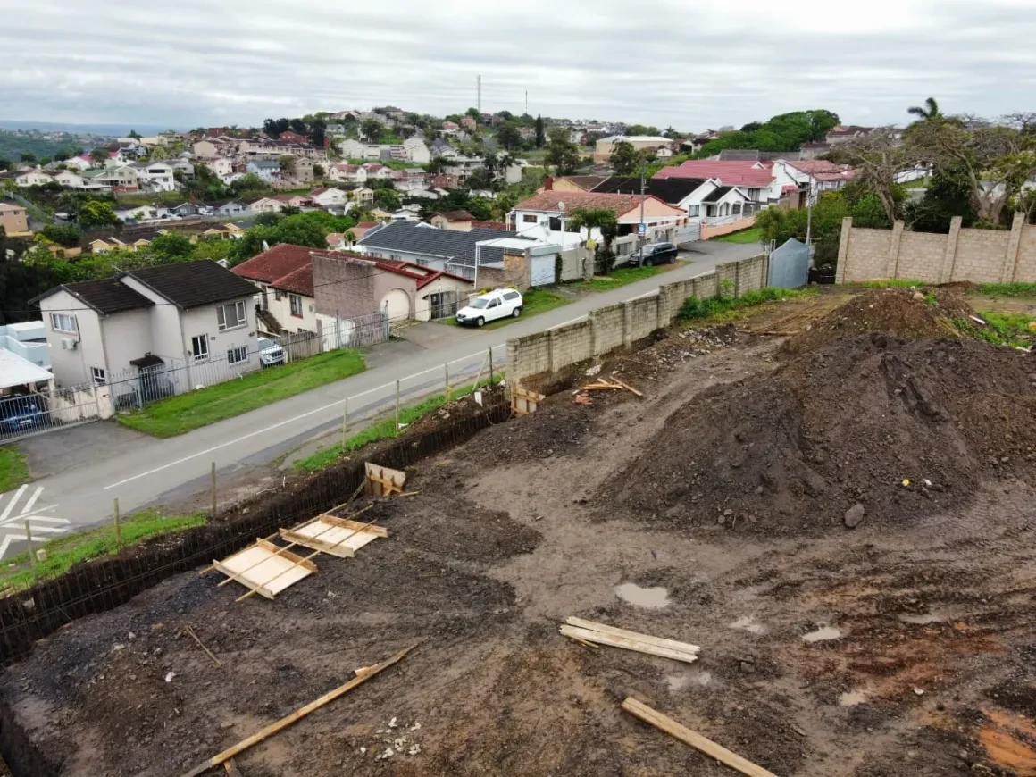 Project site — workers in trench through wire fence