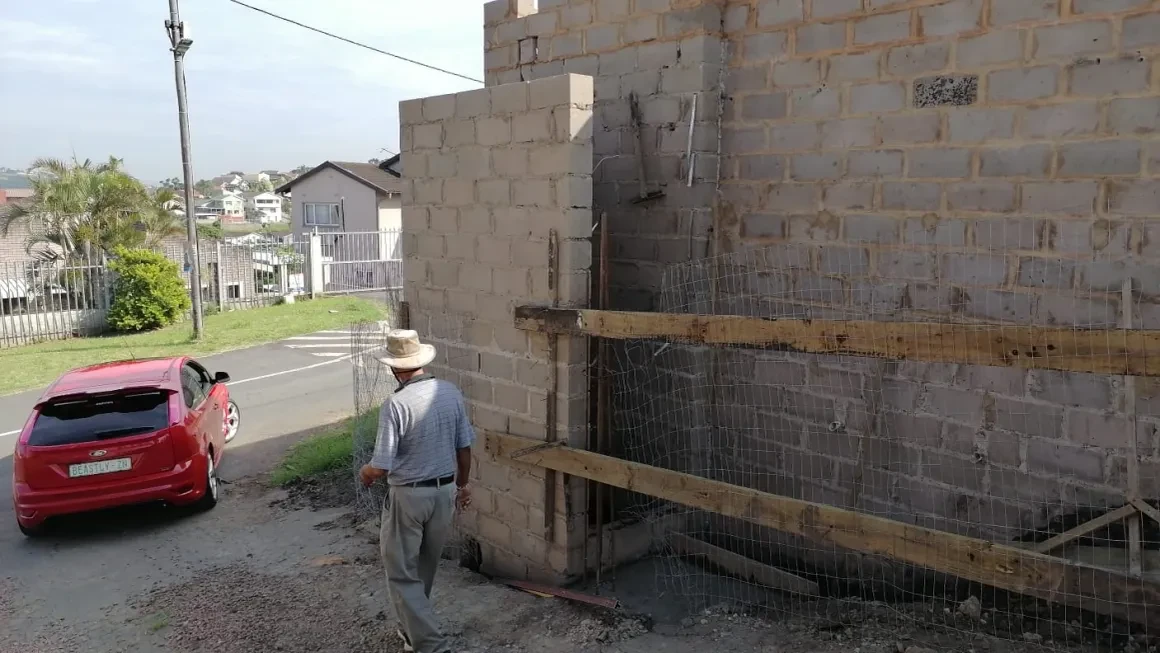 Project site — brick building under construction with red car on road