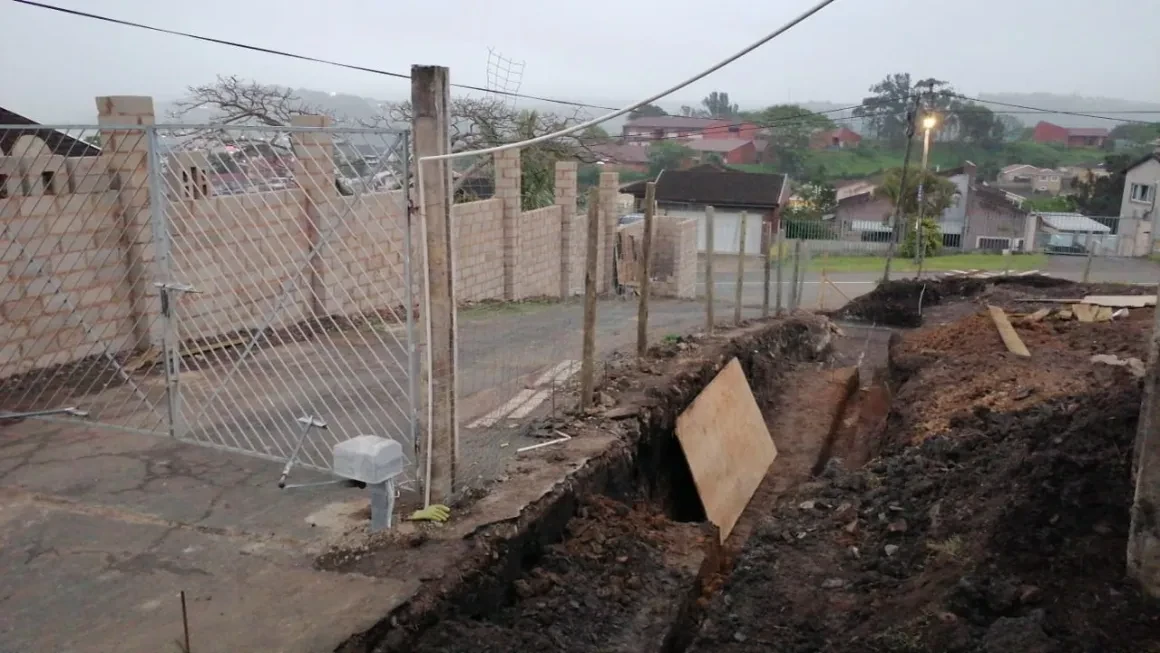 Project site — gate entrance with trench excavation in rainy weather