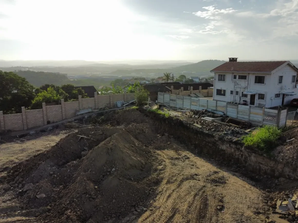 Project site — aerial view of cleared site with white house and valley