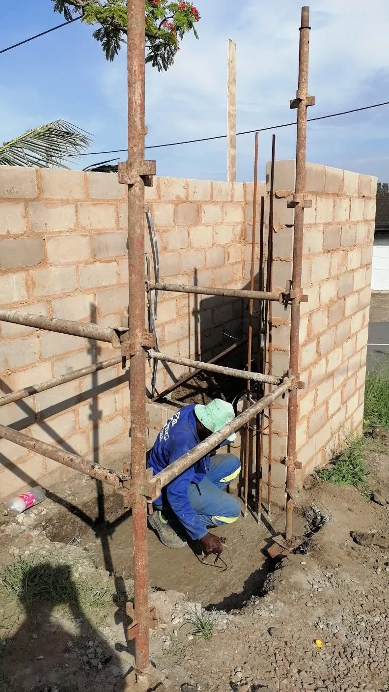 Project site — worker inside brick structure under construction with scaffolding