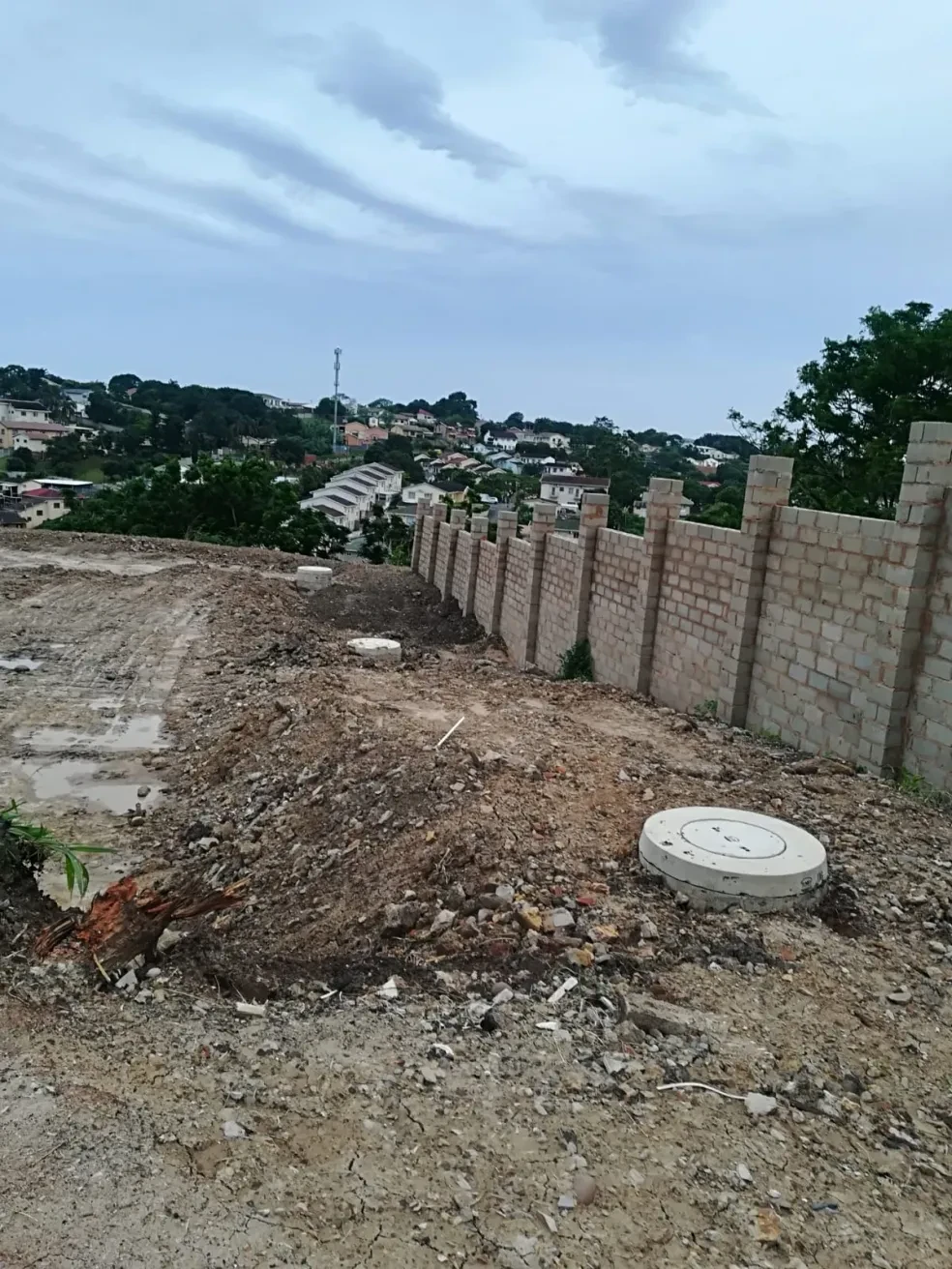 Project site — concrete block wall with hillside residential area