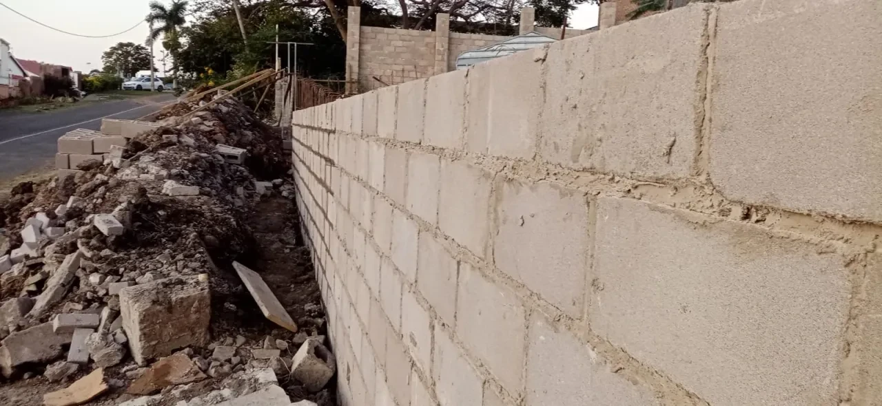 Project site — concrete block wall under development with scattered materials
