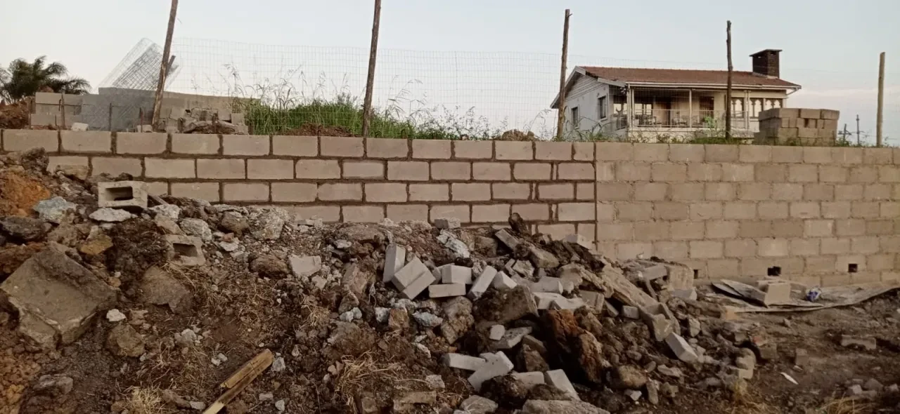 Project site — concrete block boundary wall with rubble pile