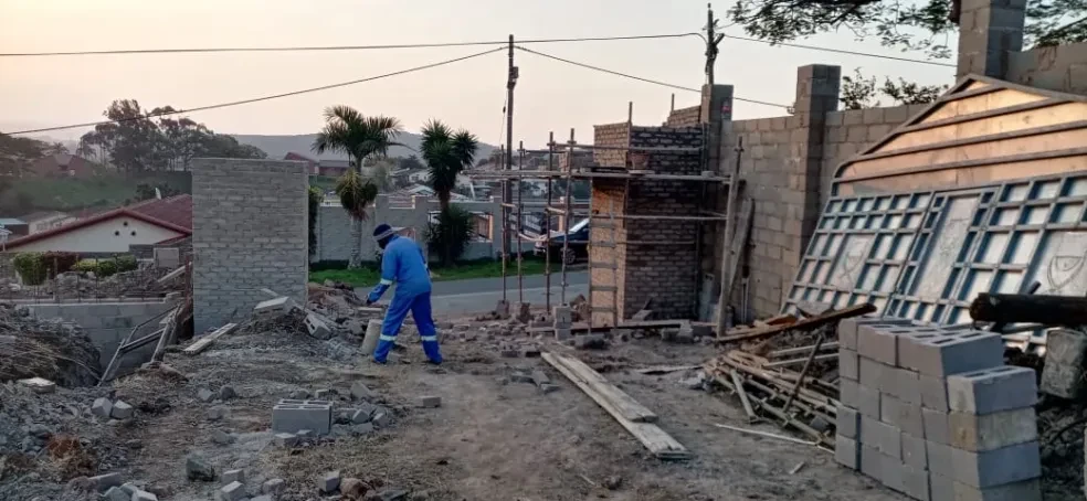 Project site — worker clearing construction site at dusk with scaffolding and block walls