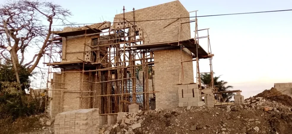 Project site — tall brick tower with extensive scaffolding at dusk