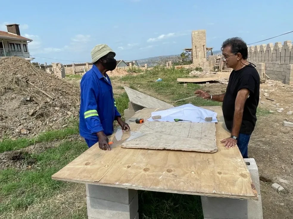 Project site — worker and supervisor reviewing plans on outdoor table