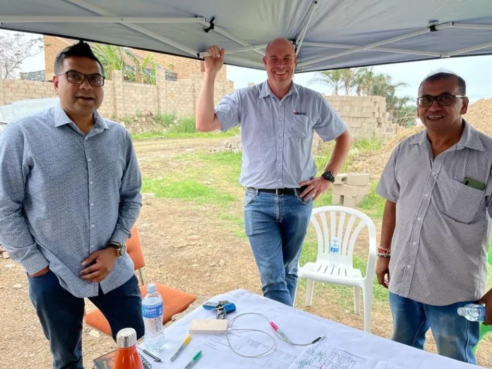 Project site — three people meeting under tent with blueprints on table