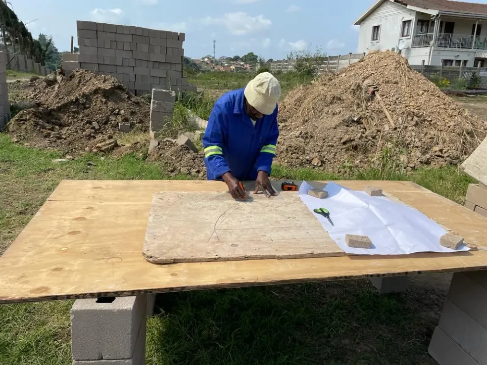 Project site — worker measuring and cutting template on outdoor workbench