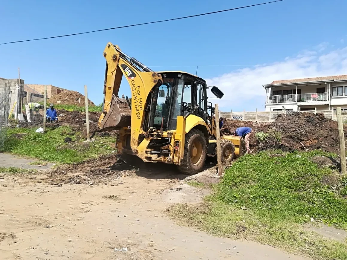 Project site — workers levelling ground with excavator