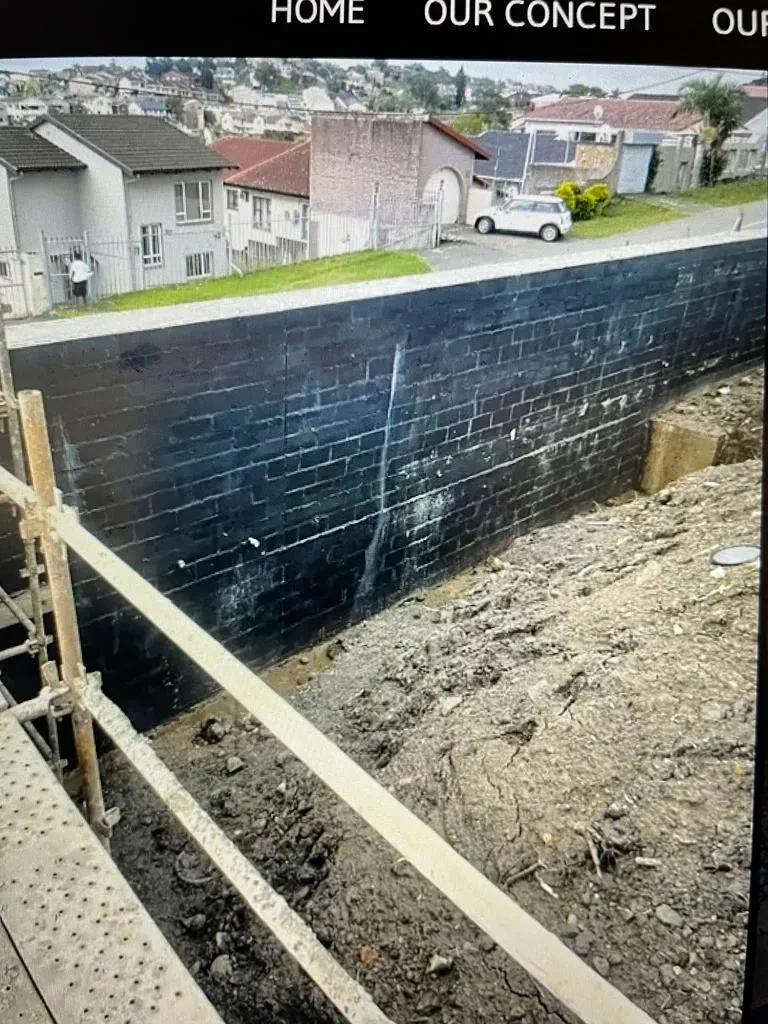 Project site — waterproofed retaining wall with scaffolding and suburban backdrop