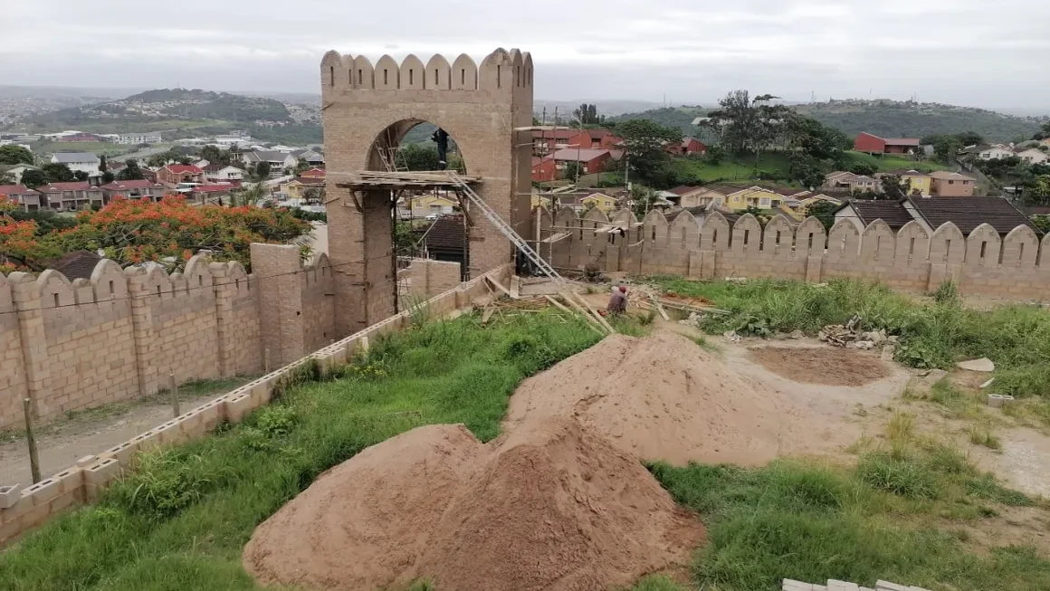 Project site — aerial view of arched gateway tower with crenellated walls and Durban hillside